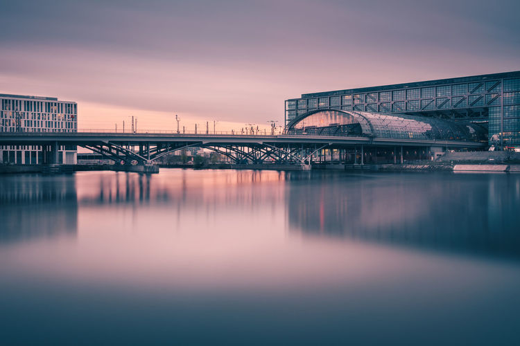 Railway bridge over river by berlin hauptbahnhof during sunset