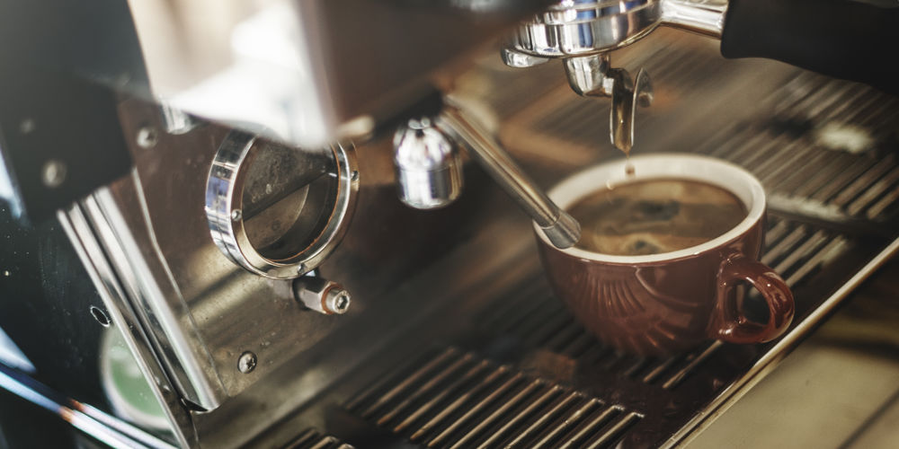 Close-up of cups on espresso maker in cafe