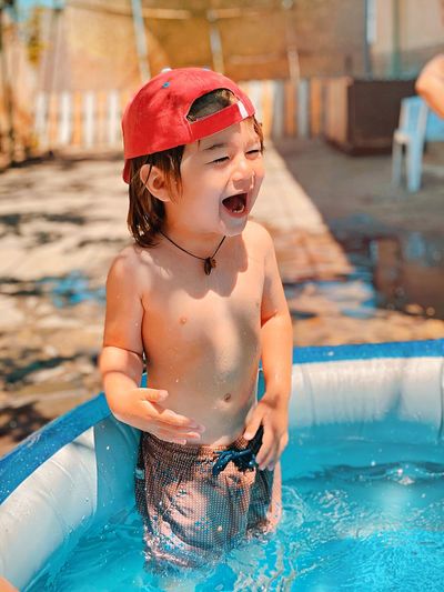 Happy shirtless boy in swimming pool