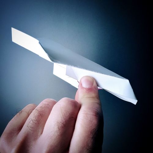 Cropped hand holding paper airplane