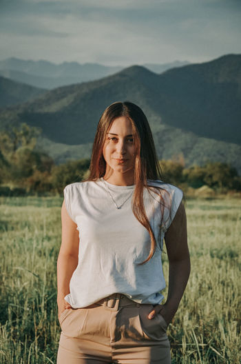 Portrait of young woman standing against mountains