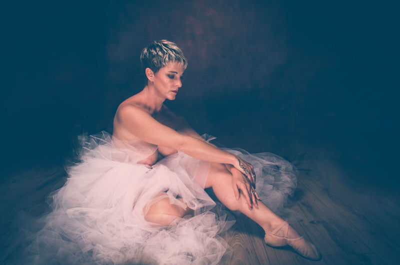 Semi-naked woman wearing tulle tutu against black background