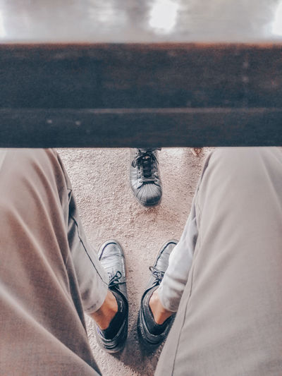 Low section of man wearing shoes while sitting outdoors