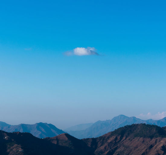 Scenic view of mountain range against blue sky
