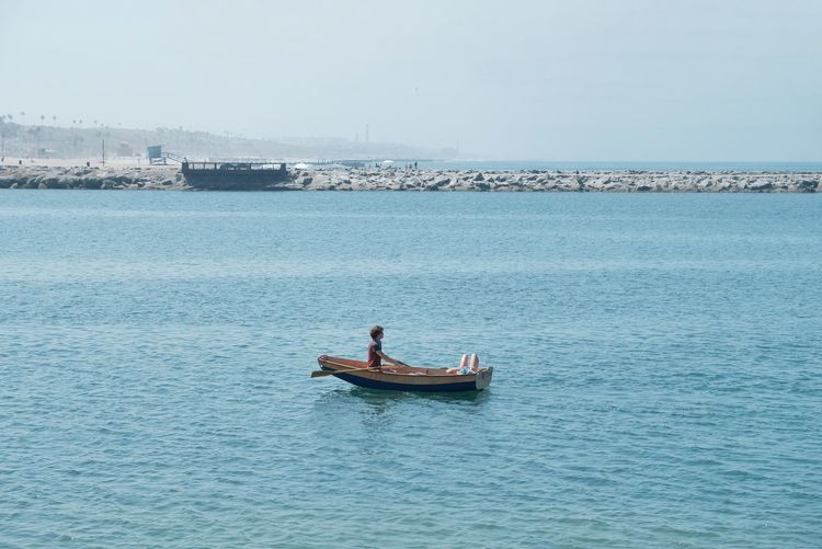 Man on boat in sea against sky