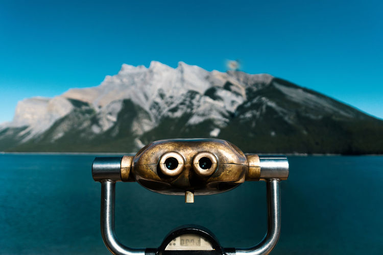 Close-up of coin-operated binoculars against mountains