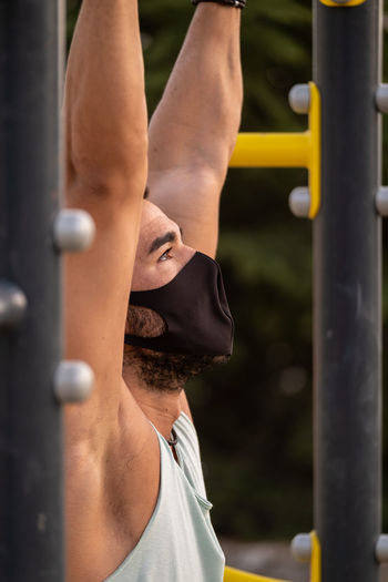 Close-up of young man wearing flu mask exercising outdoors