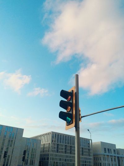 Low angle view of buildings and traffic light against sky
