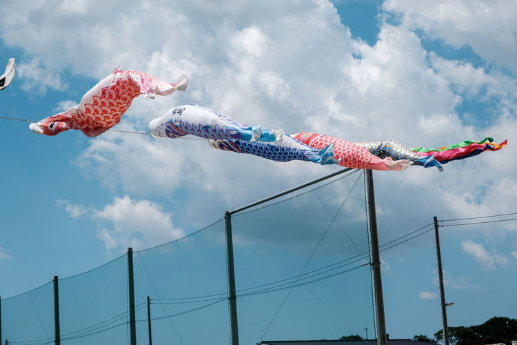 Low angle view of fish flags hanging against sky