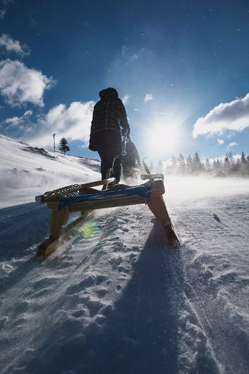Rear view of person pulling sled on snow