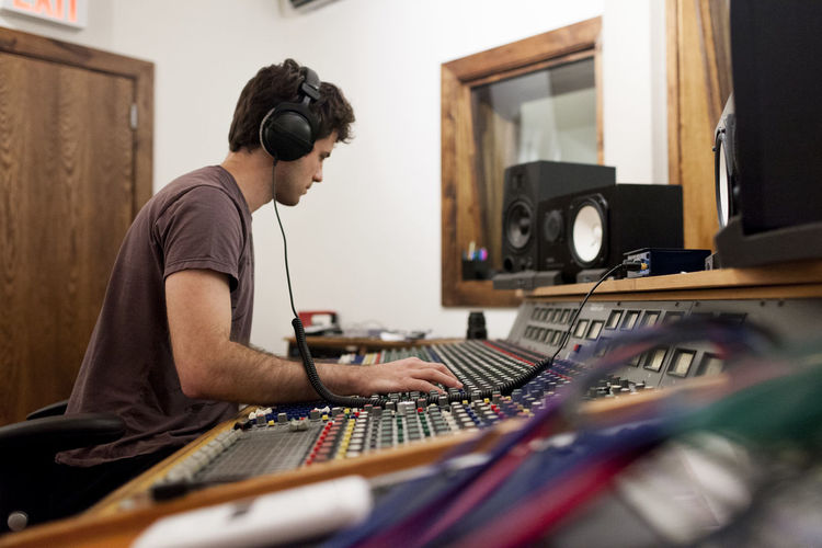 Audio engineer wearing headphones working at a mixing console