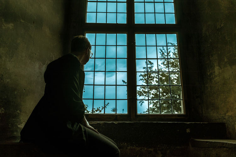 Side view of young man looking through window