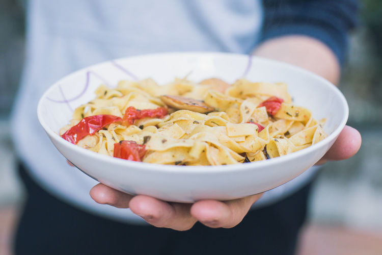 Close-up of hand holding pasta in bowl
