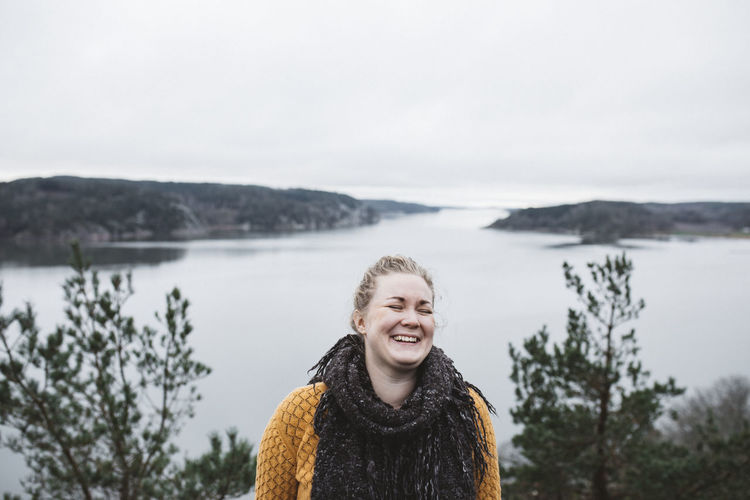 Portrait of smiling woman in lake against sky