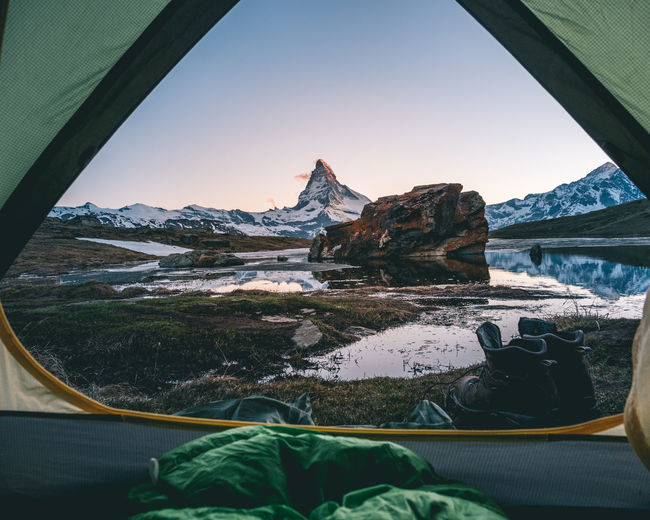 Scenic view of lake and snowcapped mountain against sky seen through tent