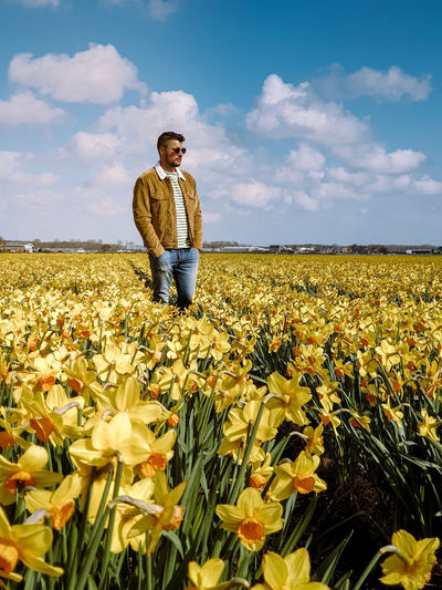 Full length of man standing on field ow yellow flowers 