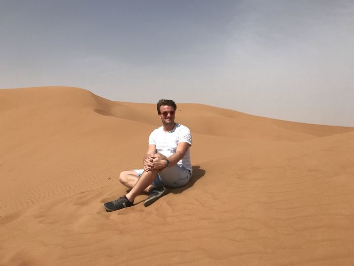 Full length of man on sand in desert against sky