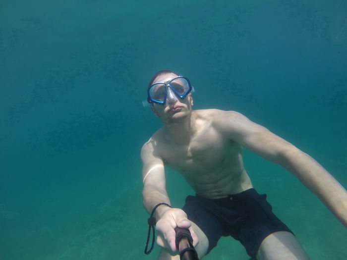 Shirtless man taking selfie in sea