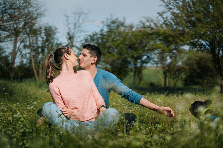 Couple kissing in blooming field against trees