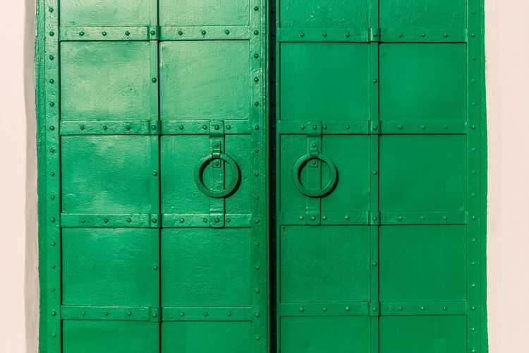 Green riveted iron double door covered with fresh green paint