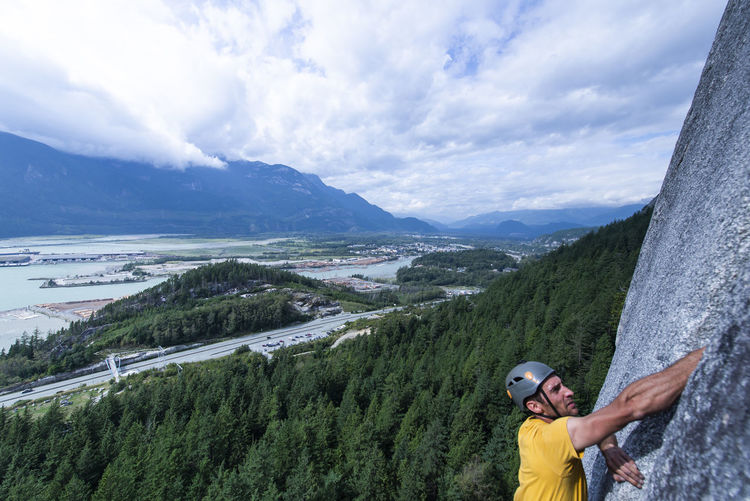 Man blurry foreground climbing with squamish city forest background