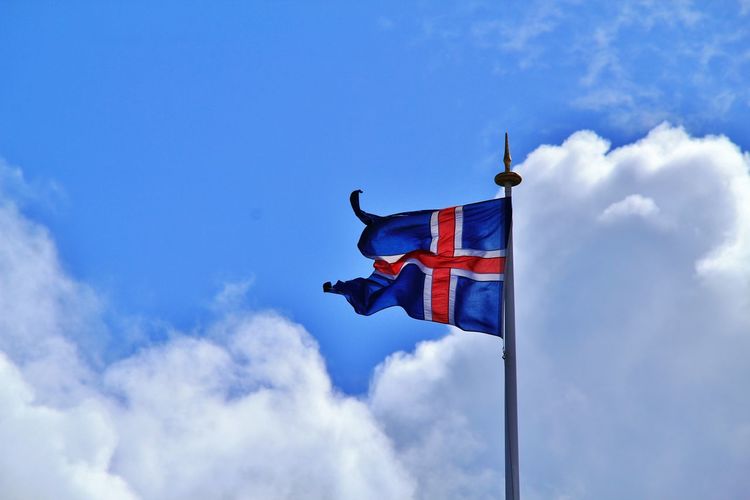 Low angle view of icelandic flag against blue sky and clouds