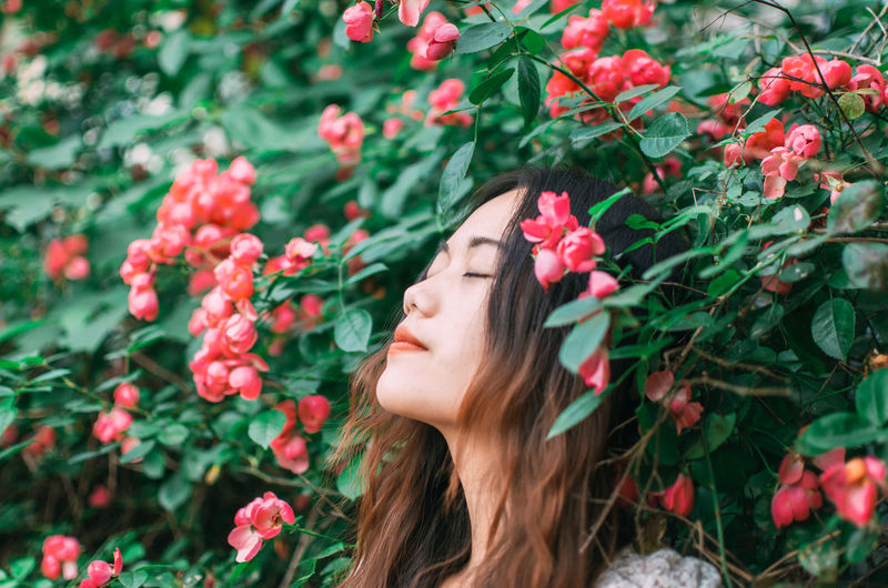 Portrait of young woman day dreaming by flower bush