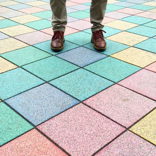 Low section of man standing on colorful paved walkway