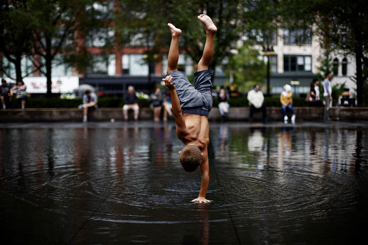 Full length of boy doing handstand in city during rainy season