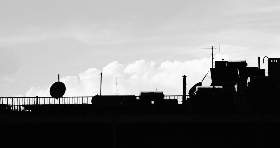 Low angle view of silhouette built structures against cloudy sky