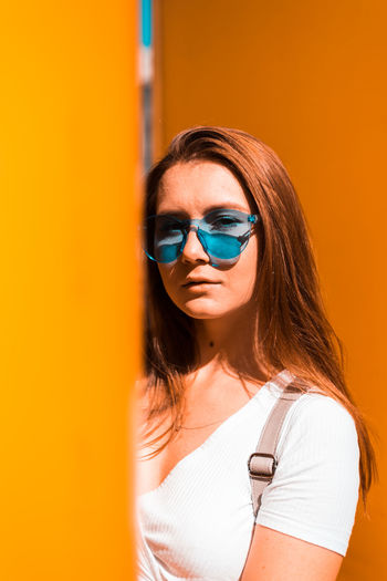 Portrait of beautiful woman standing against orange wall