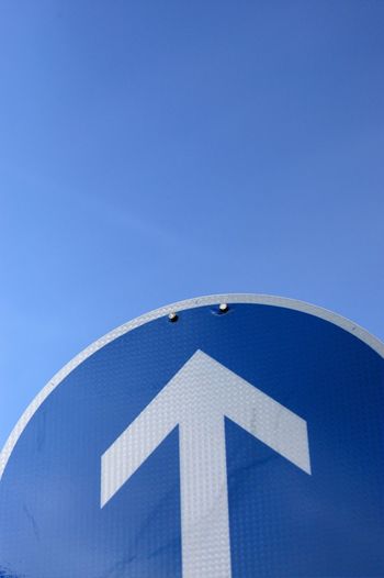 Low angle view of arrow symbol against clear blue sky
