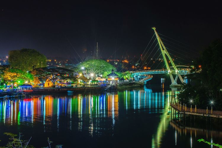 Illuminated boats moored in river at night