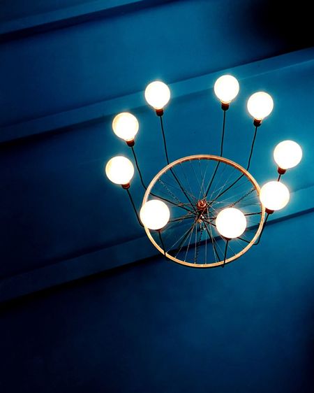 Low angle view of illuminated light bulb hanging on ceiling