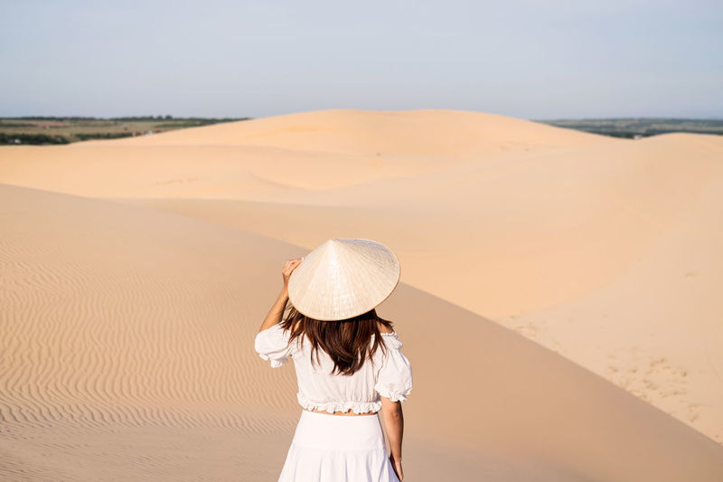 Woman standing on sand dune against the sky