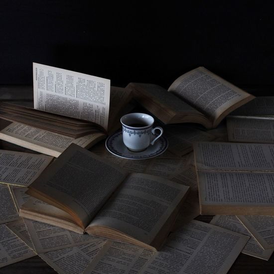 High angle view of tea cup amidst open books on desk