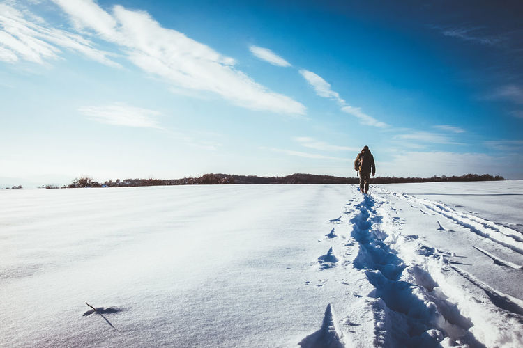 Man standing on snow covered land against sky