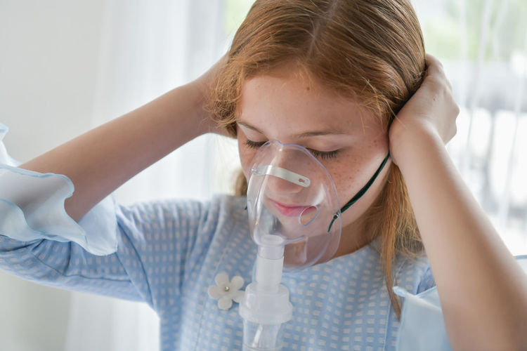 Close-up of girl wearing oxygen mask in hospital ward
