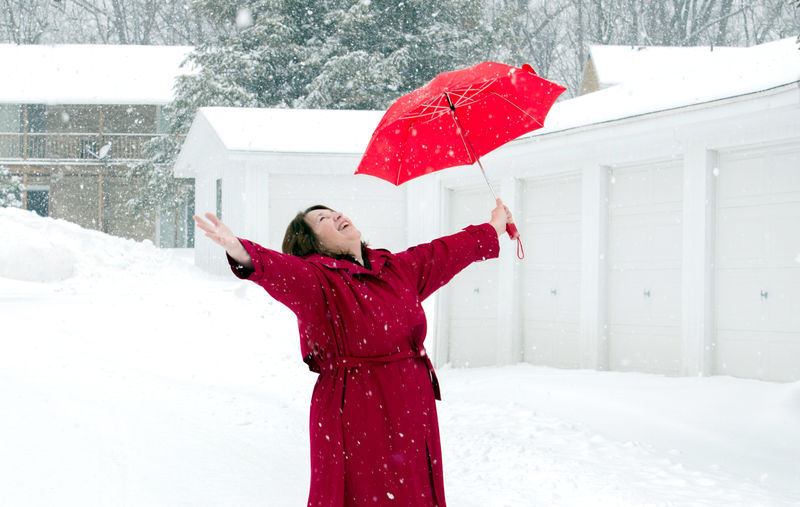 A happy woman in red with a umbrella, enjoys being out on a snowy winter's day