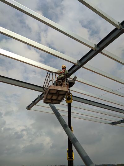 Low angle view of man working against sky