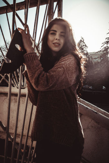 Portrait of young woman standing on railing