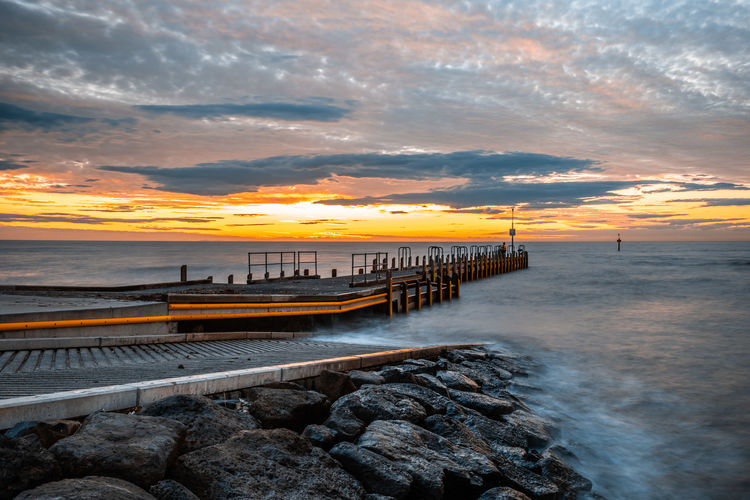 Small pier extending into silky smooth ocean at sunset - long exposure seascape