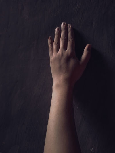 Close-up of human hand touching wall