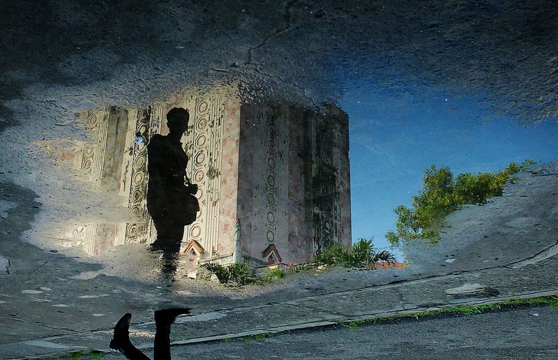 Reflection of man in water against sky