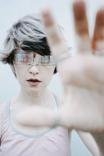 Androgynous woman gesturing wearing futuristic glasses against white background