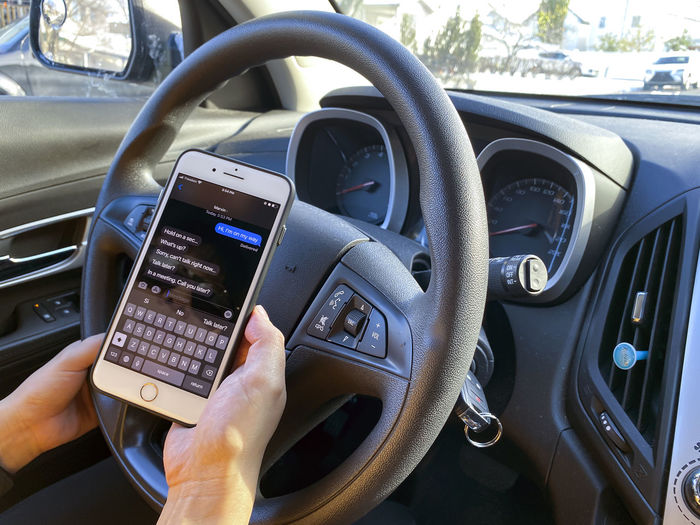 Midsection of person using mobile phone in car