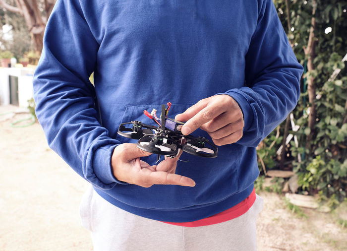 Young man prepares the battery of his drone in the field to go fly