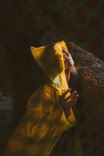Woman hiding from the rain in a yellow raincoat