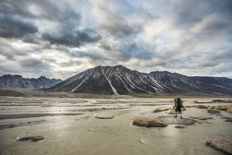Backpacker navigates crossing a braided river in a high mountain pass.