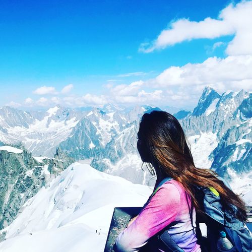 Rear view of woman on snowcapped mountains against sky